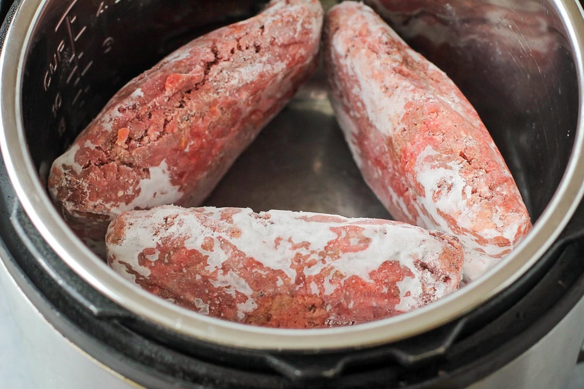 Three cubes of frozen ground beef in an instant pot.