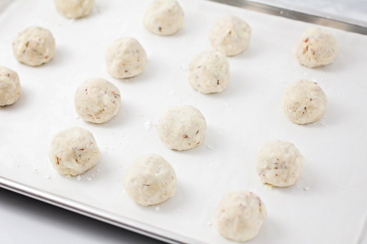 Baked dough balls on a lined baking sheet.