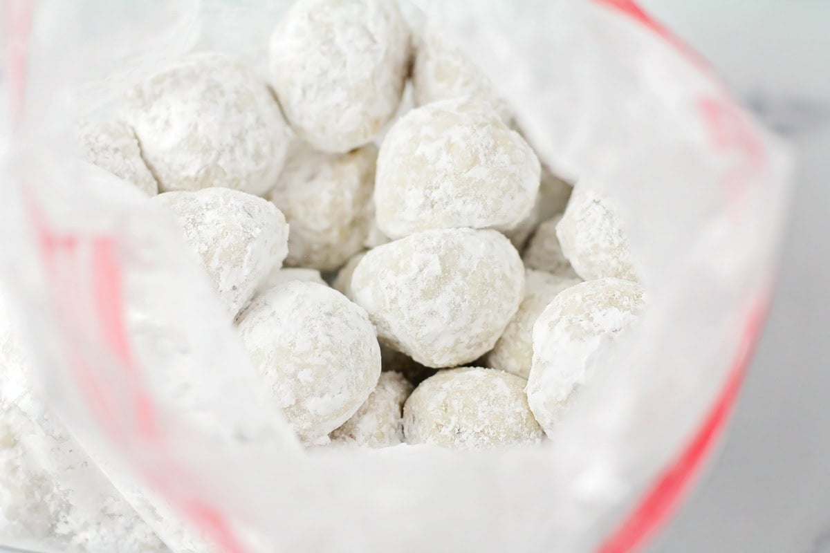 Coating Mexican wedding balls in a bag of powdered sugar.