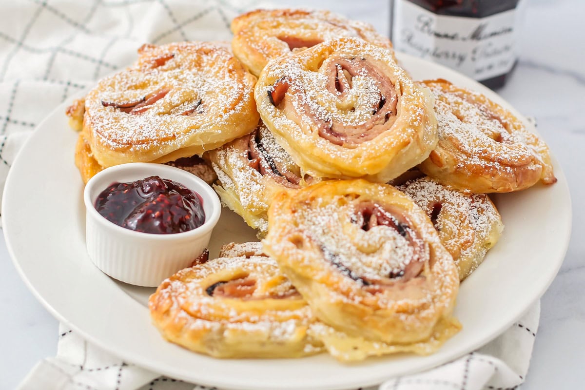 A plate of monte cristo pinwheels served with jam.