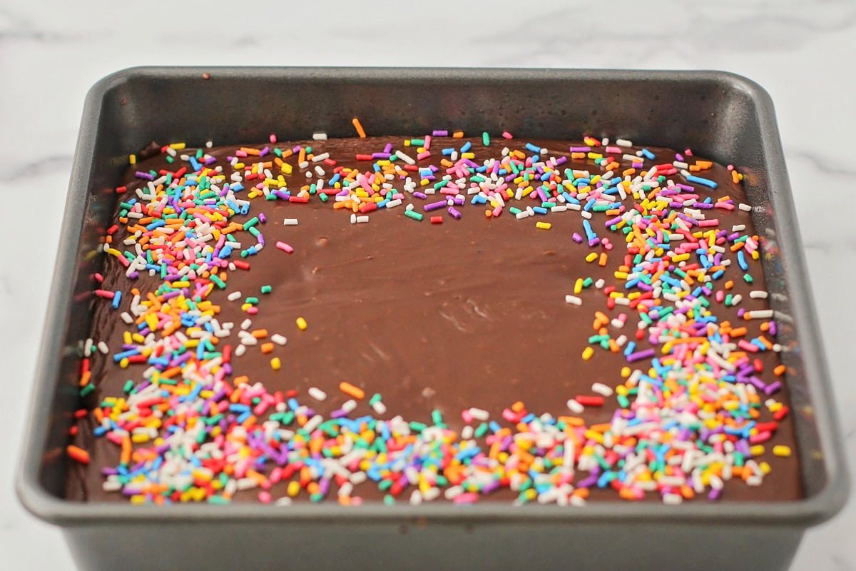 A baked and frosted cake topped with sprinkles.