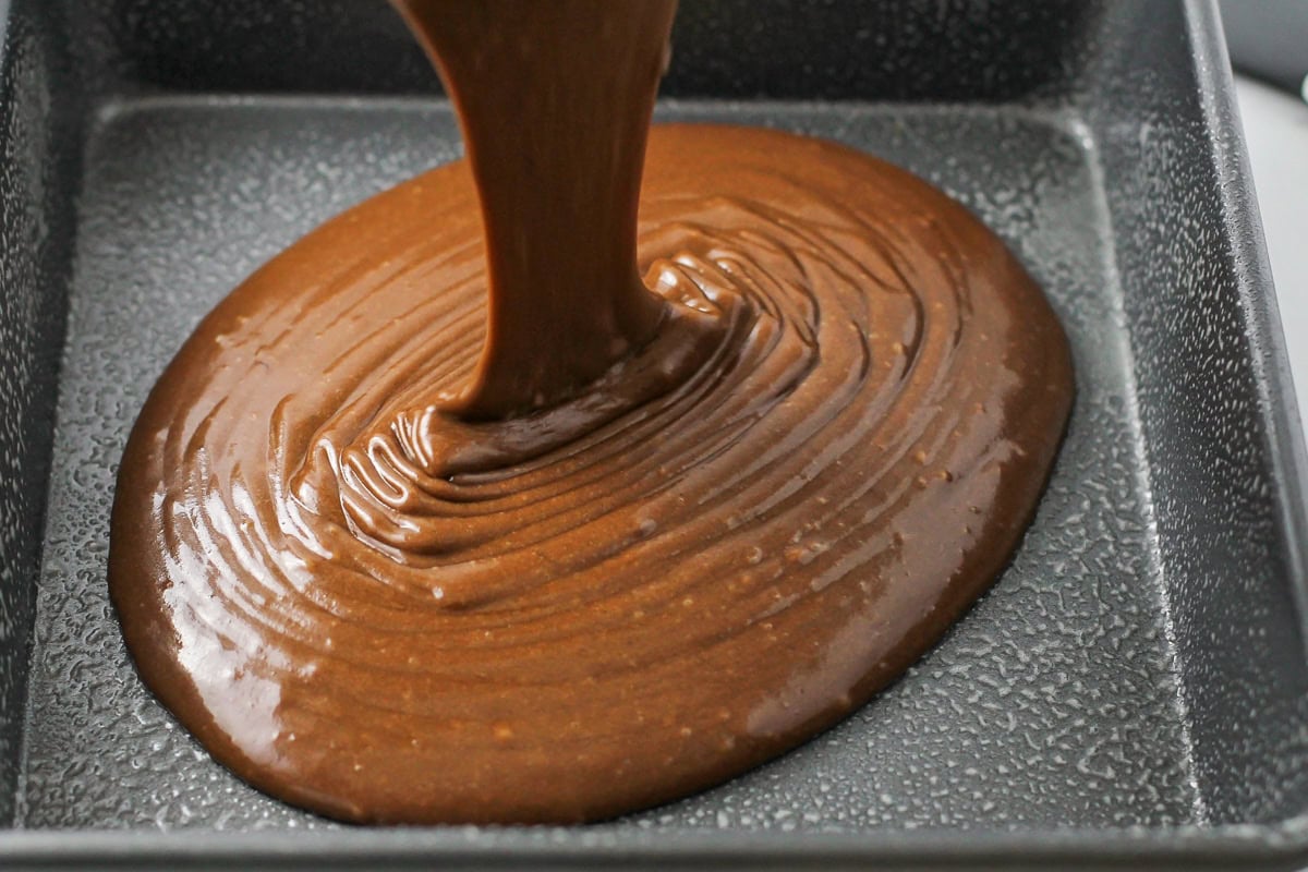 Pouring cake batter in a greased pan.