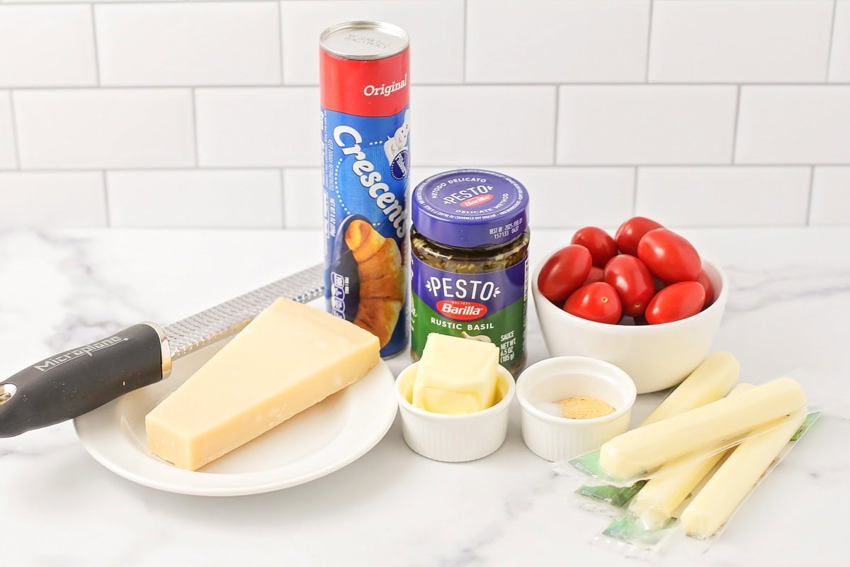 Cheese, croissants, tomatoes, and other ingredients on a kitchen counter.