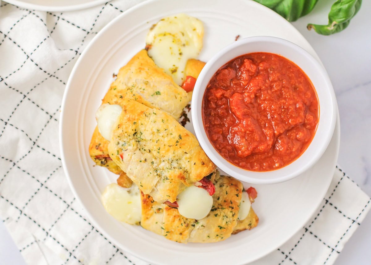 Top view of three pesto caprese croissants served with marinara.