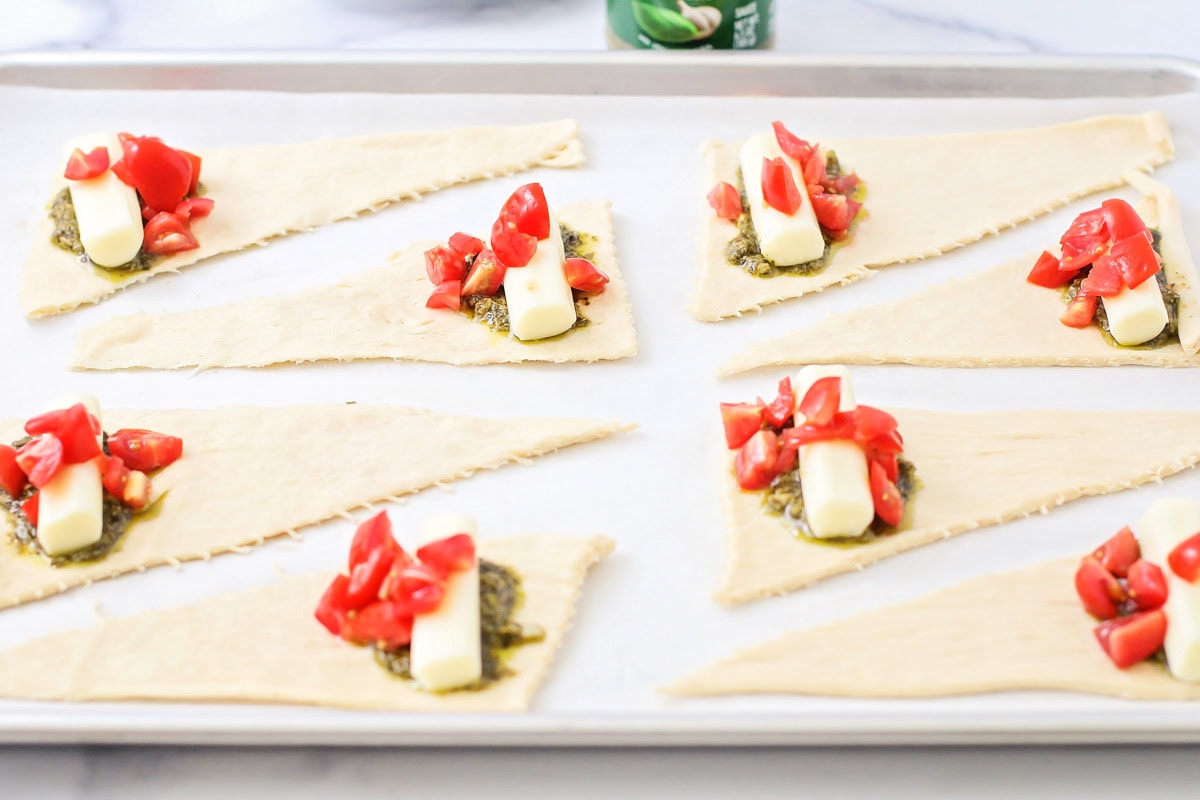 Topping the pesto with a mozzarella stick and tomatoes.