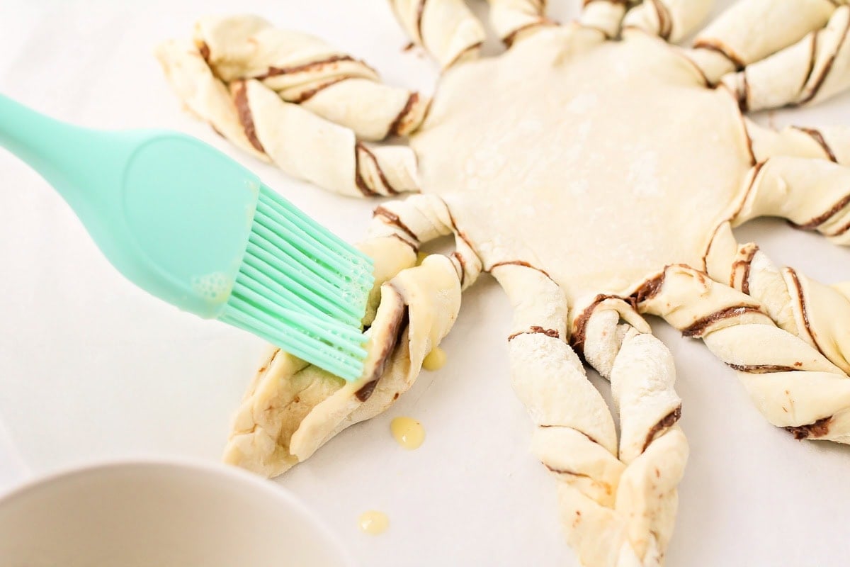 Adding egg wash to the puff pastry snowflake.