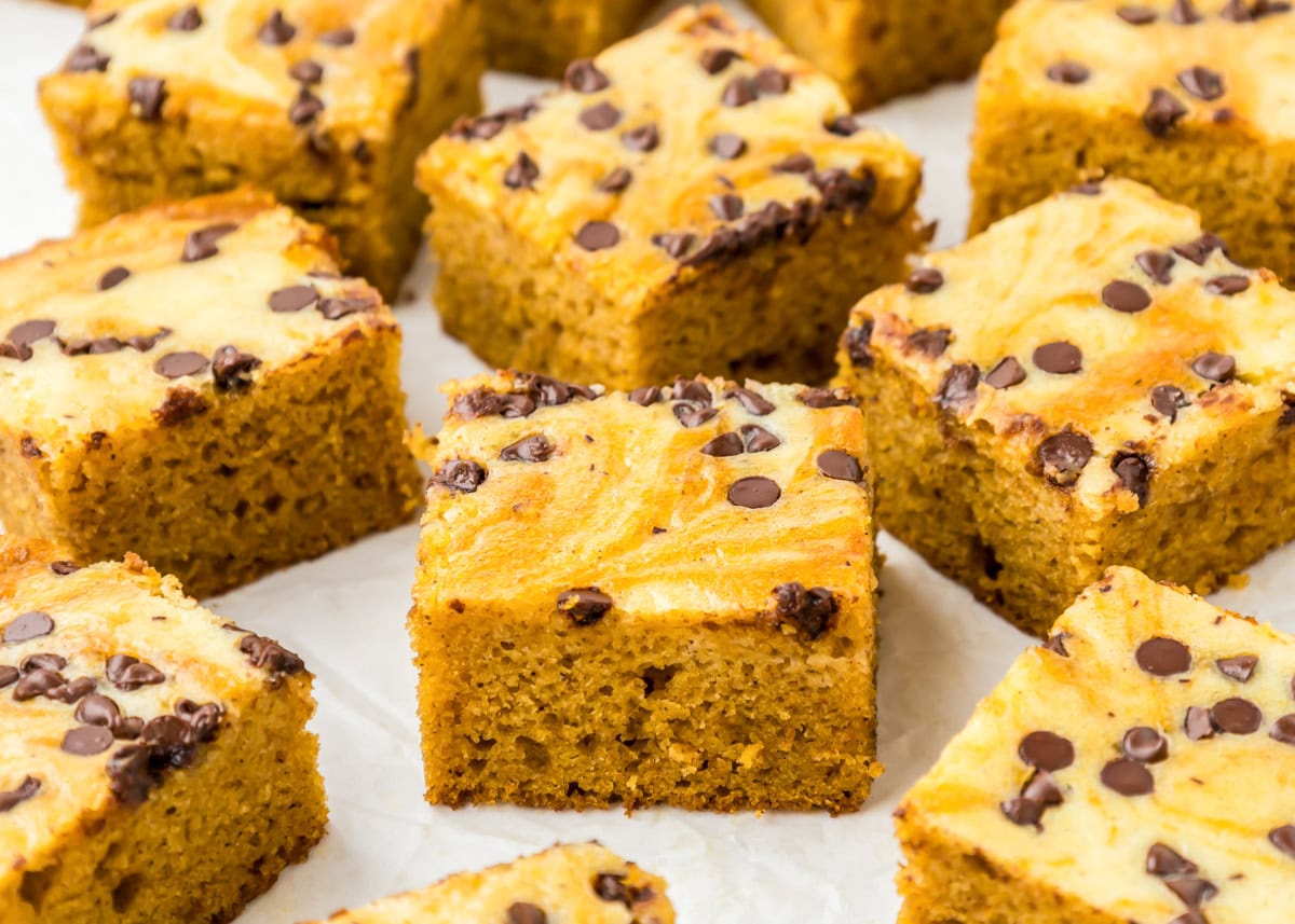 Pumpkin cream cheese bars on white parchment paper.