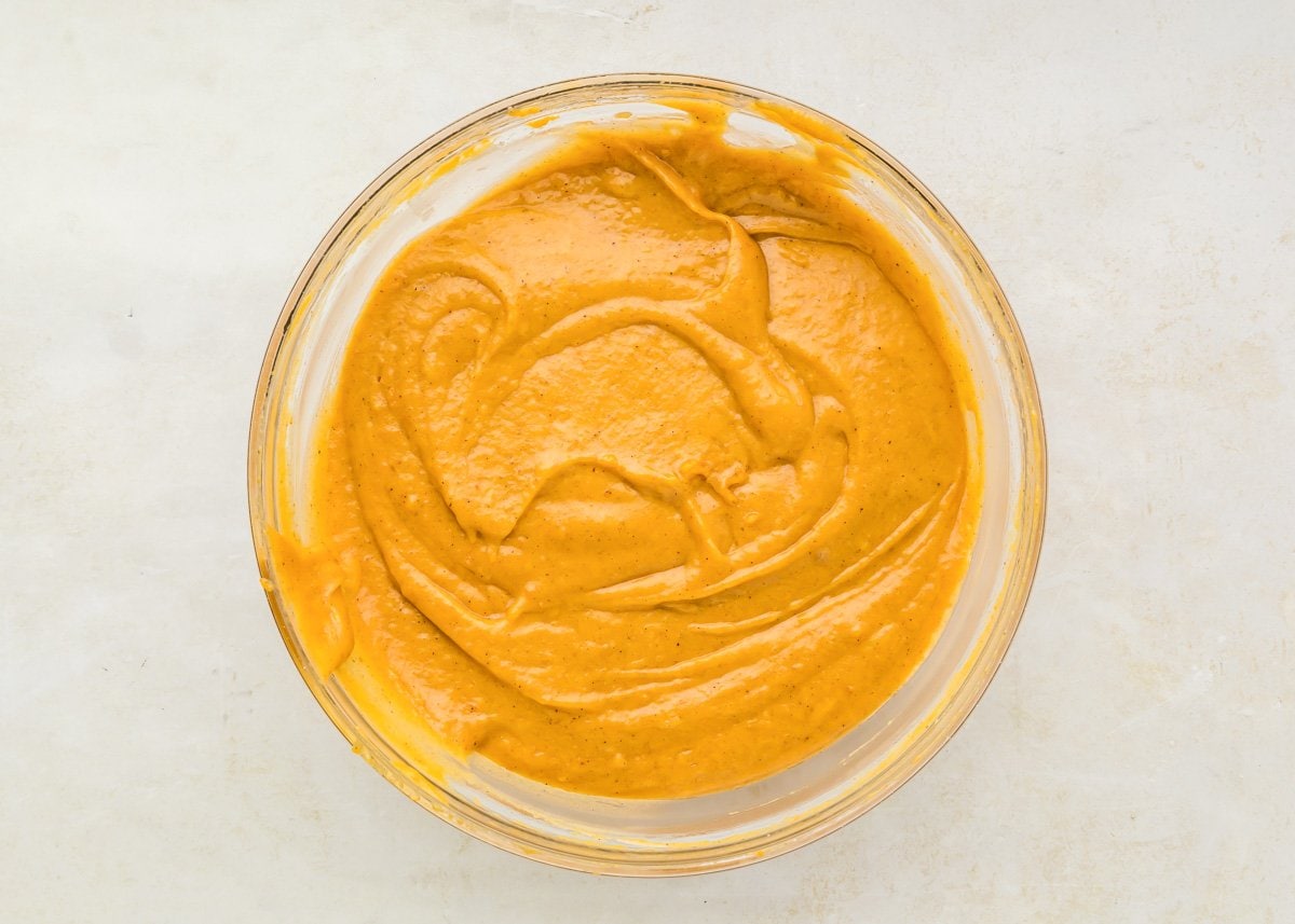 Pumpkin portion of pumpkin cream cheese bars mixed together in glass bowl.