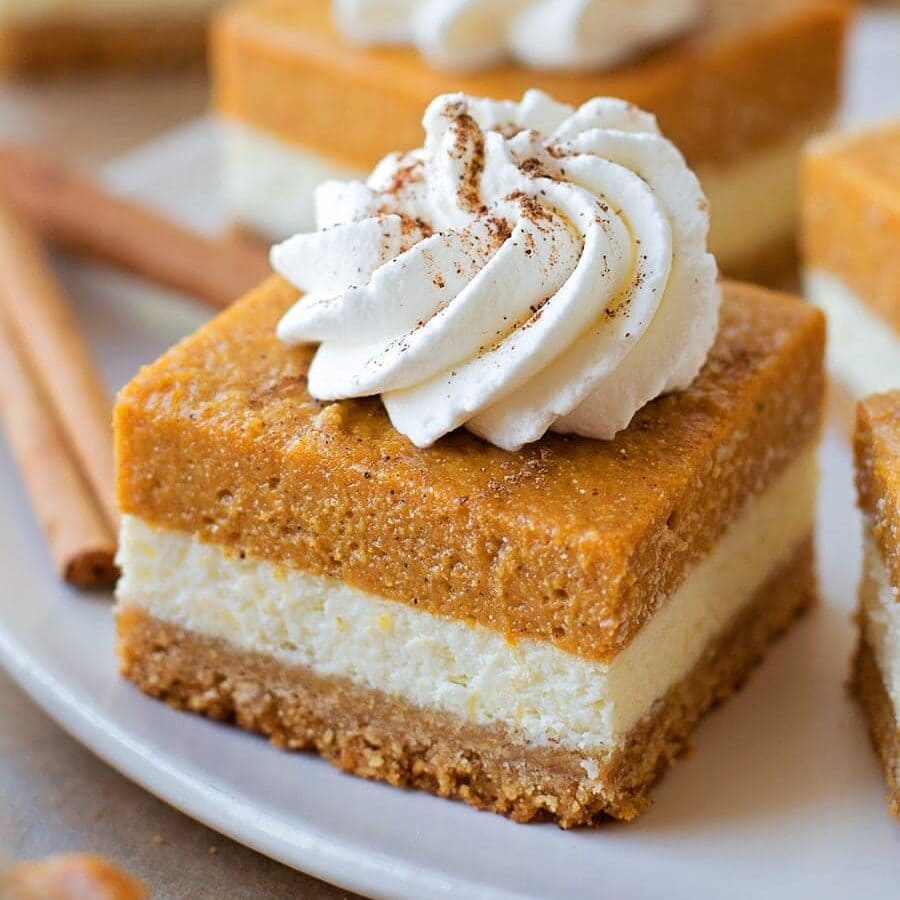 Close up image of pumpkin cheesecake bars slice on white plate.