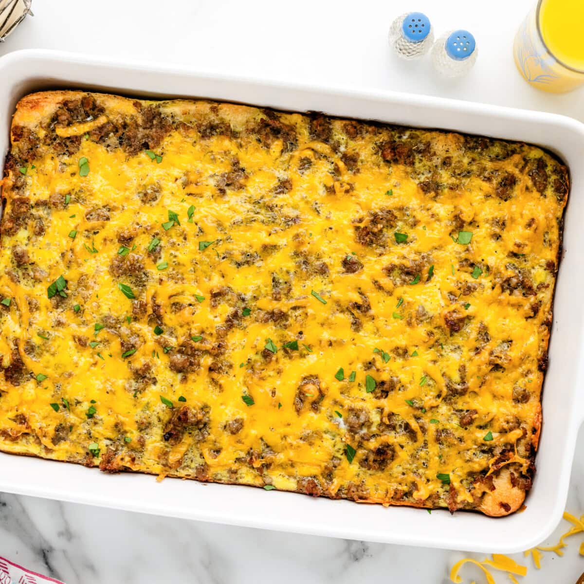 Sausage breakfast casserole baked in dish with ingredients around it.