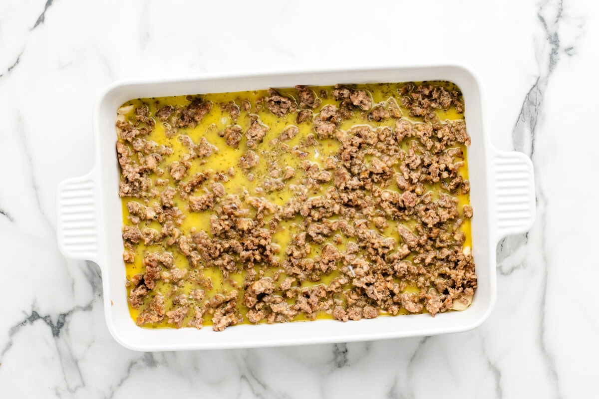 Pouring the egg mixture of the sausage and crescent roll.