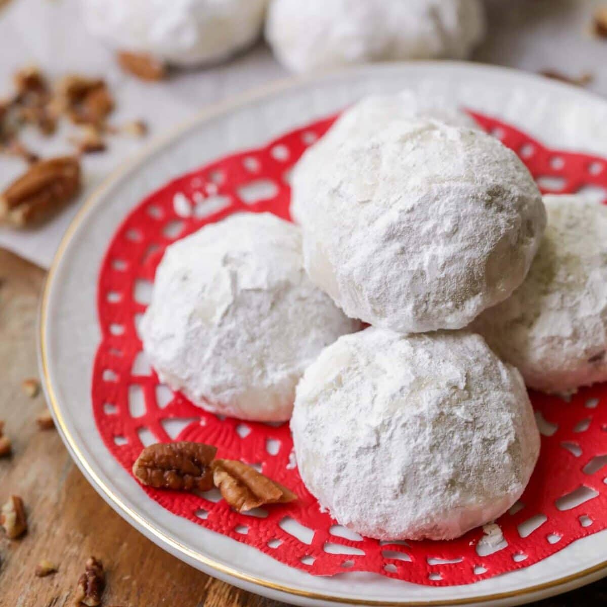 Snowball cookies stacked on top of each other on white plate.