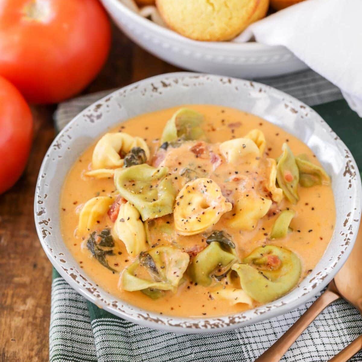 Square image of crock pot tortellini soup recipe with pepper on top.