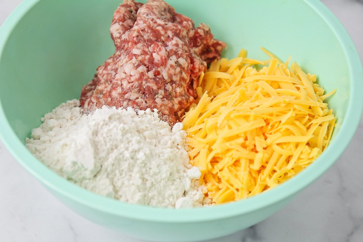 Ingredients for Bisquick sausage balls in a mixing bowl.