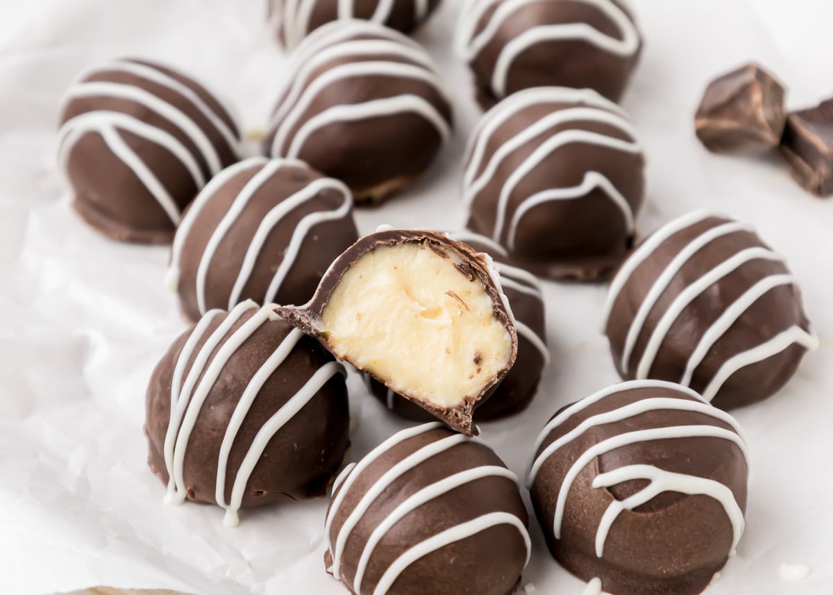 Cheesecake Bites with one cut in half on top of other bites on parchment paper.