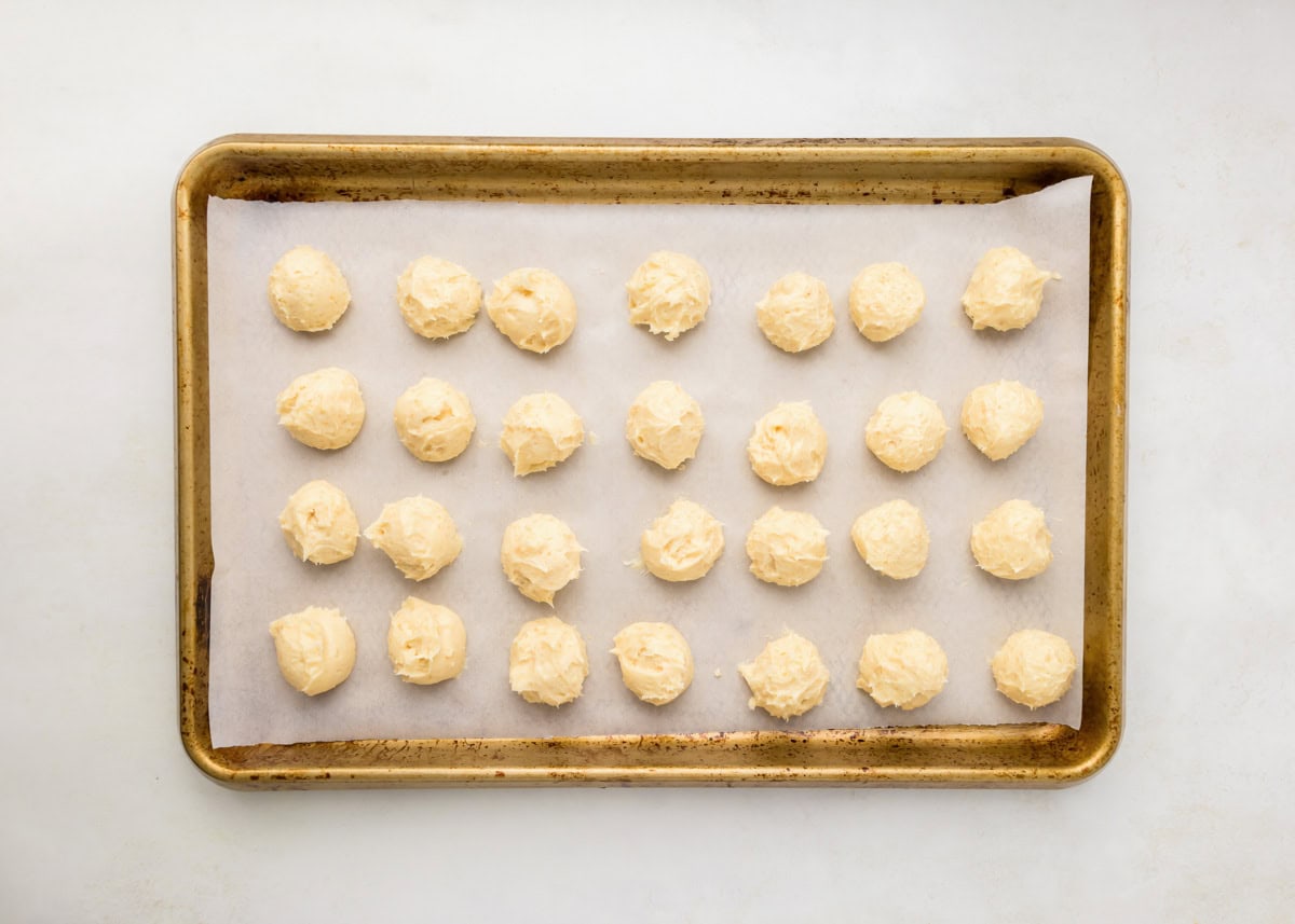 Cheesecake scoops on parchment paper lined baking sheet.