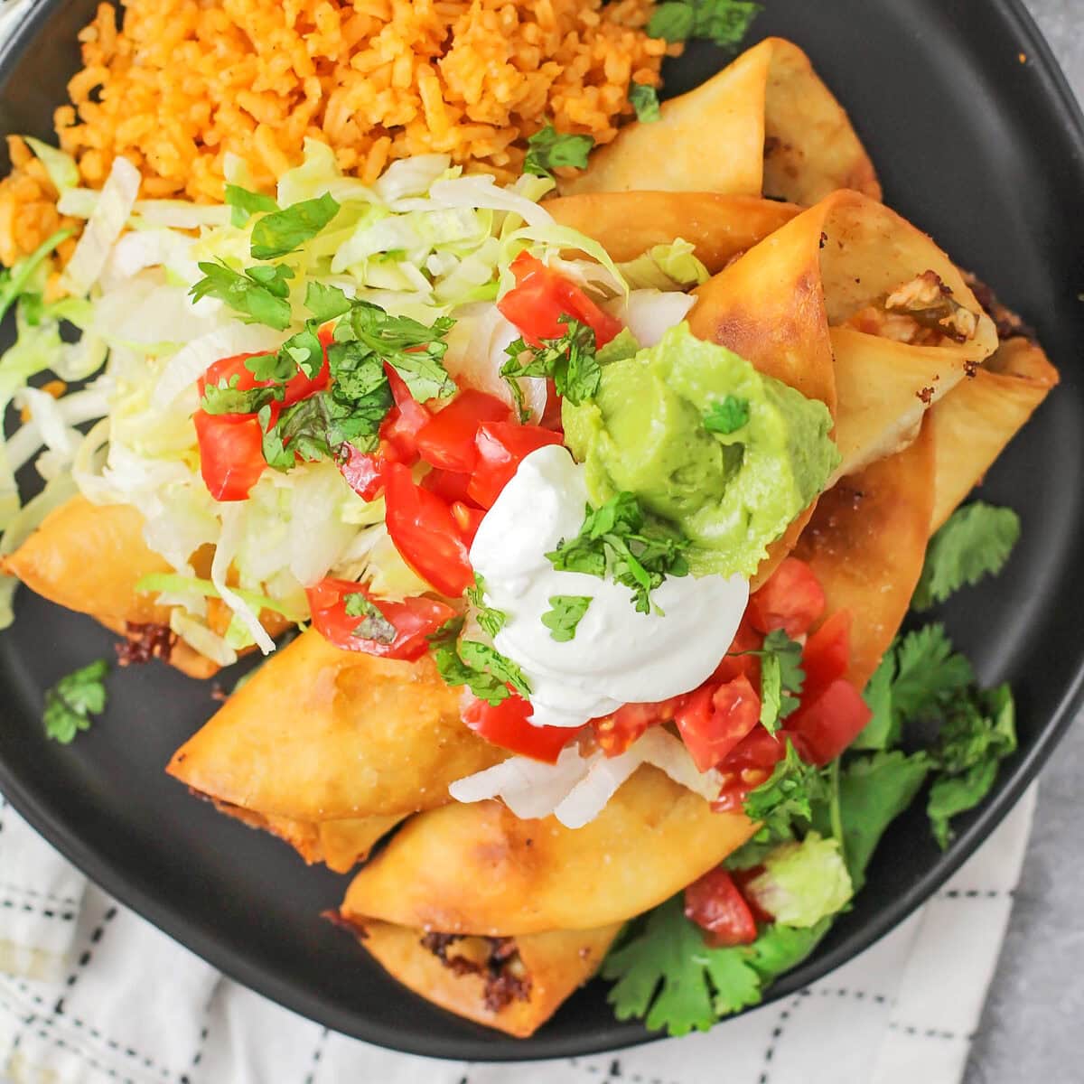 Chicken flautas with toppings and Spanish rice on the side.