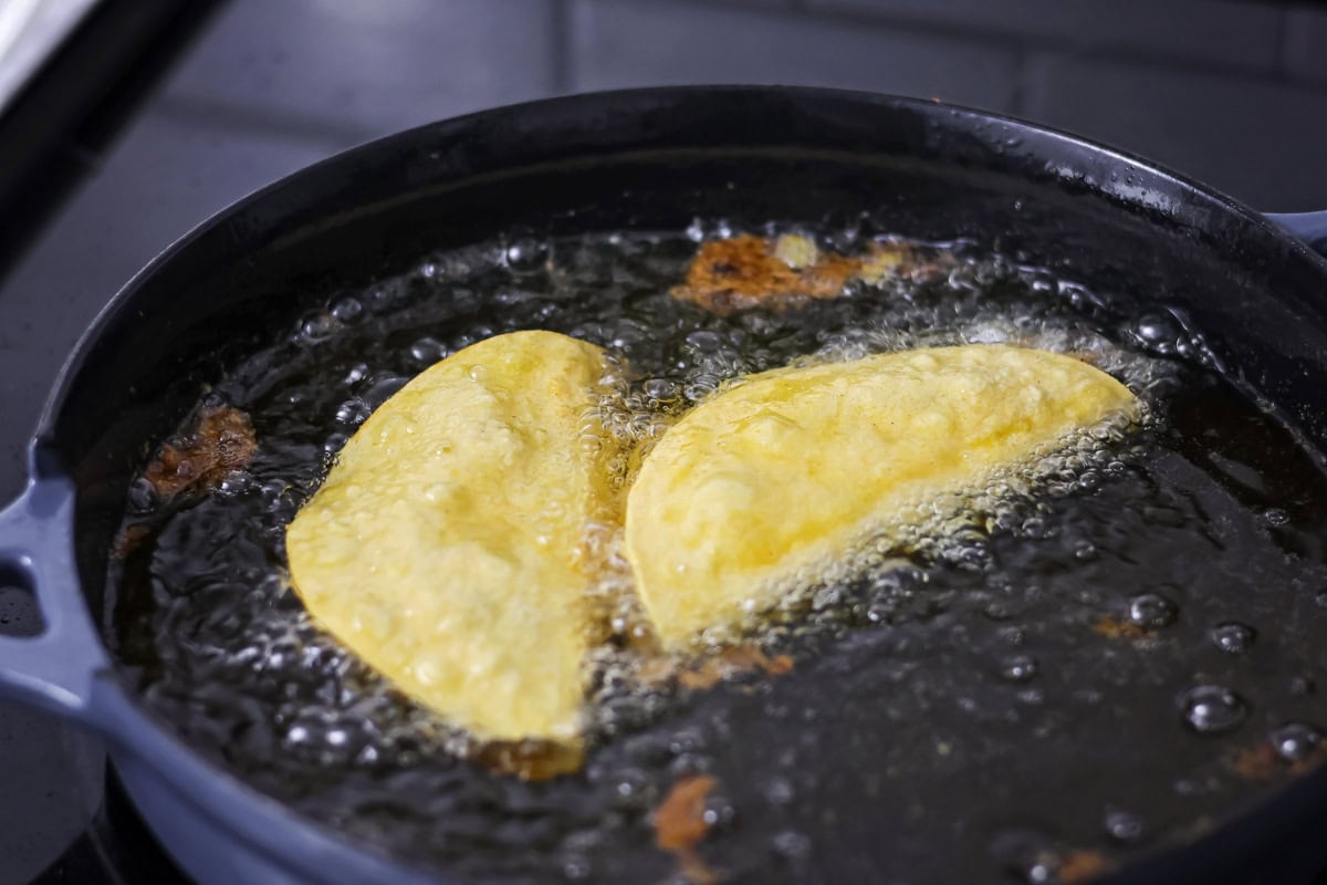 Chicken tacos being fried in oil.