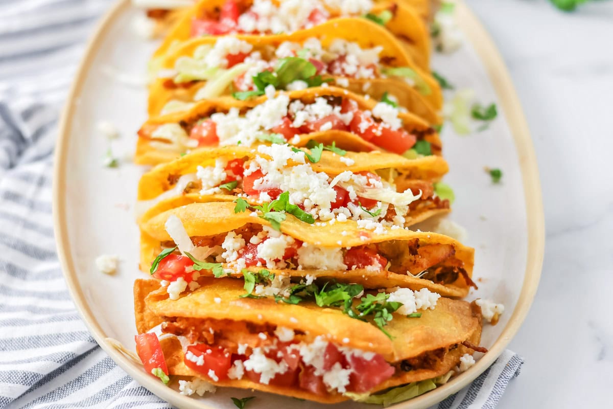 Chicken tacos on white serving platter.