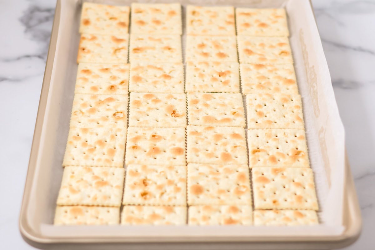 Saltine crackers spread over baking sheet with parchment paper.