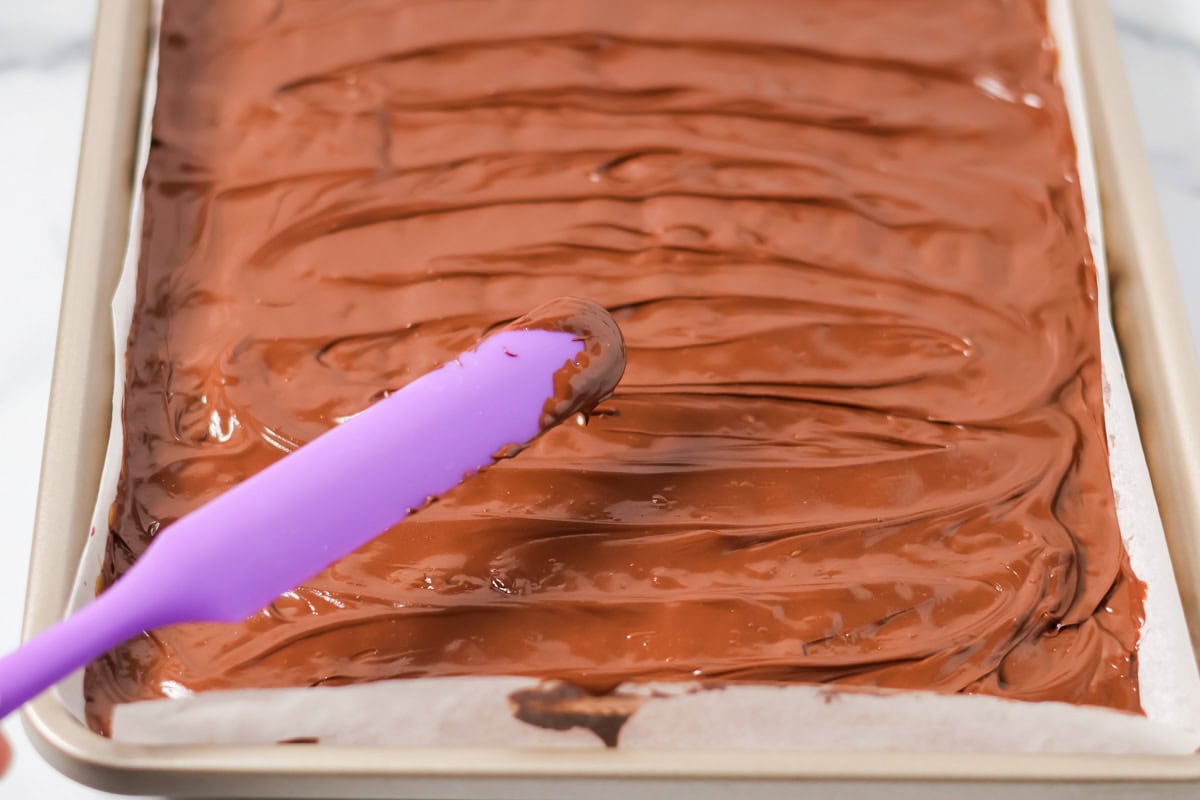 Chocolate being spread over toffee layer of Christmas crack.