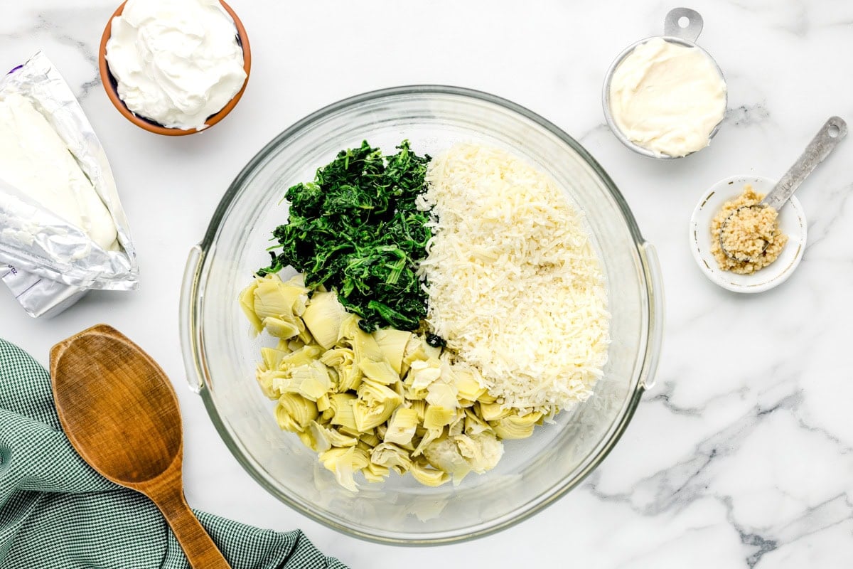 Spinach, artichokes, and cheese in a mixing bowl.