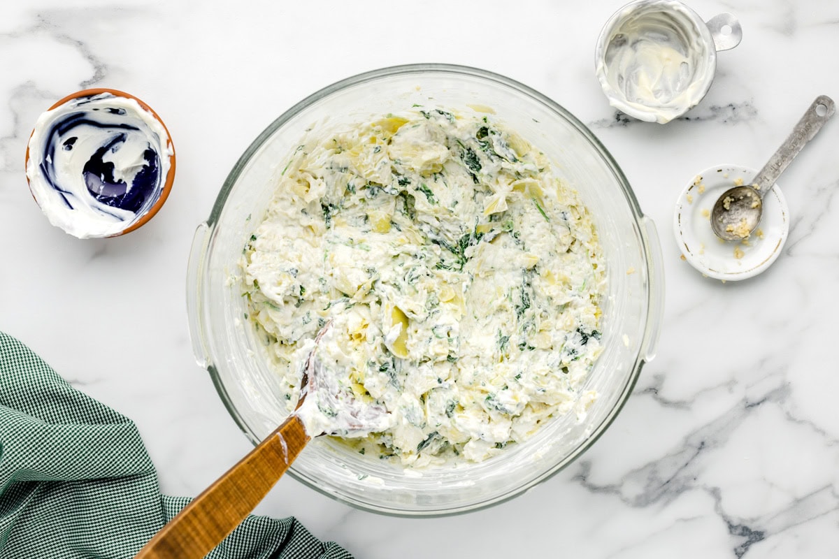 Crock pot spinach artichoke dip ingredients mixed together in bowl.