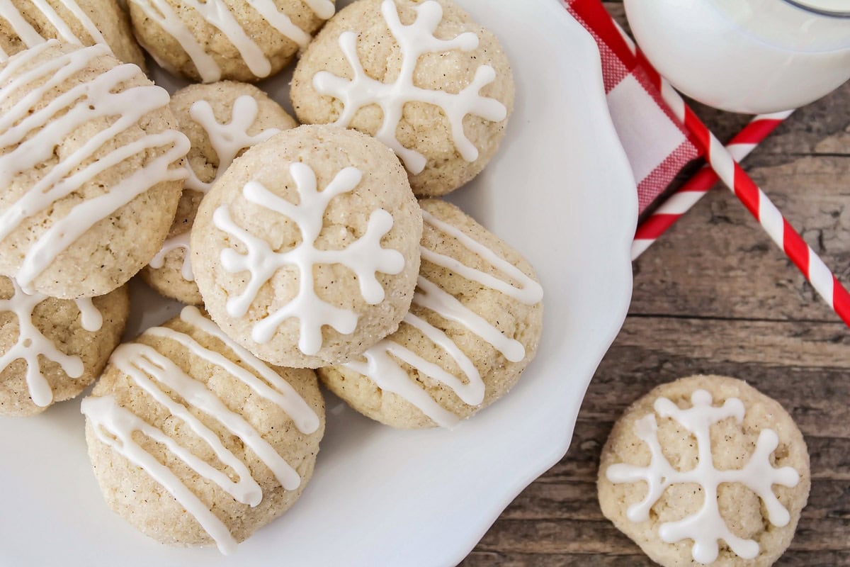 Eggnog snickerdoodles on white cookie plate with glaze drizzled on top.