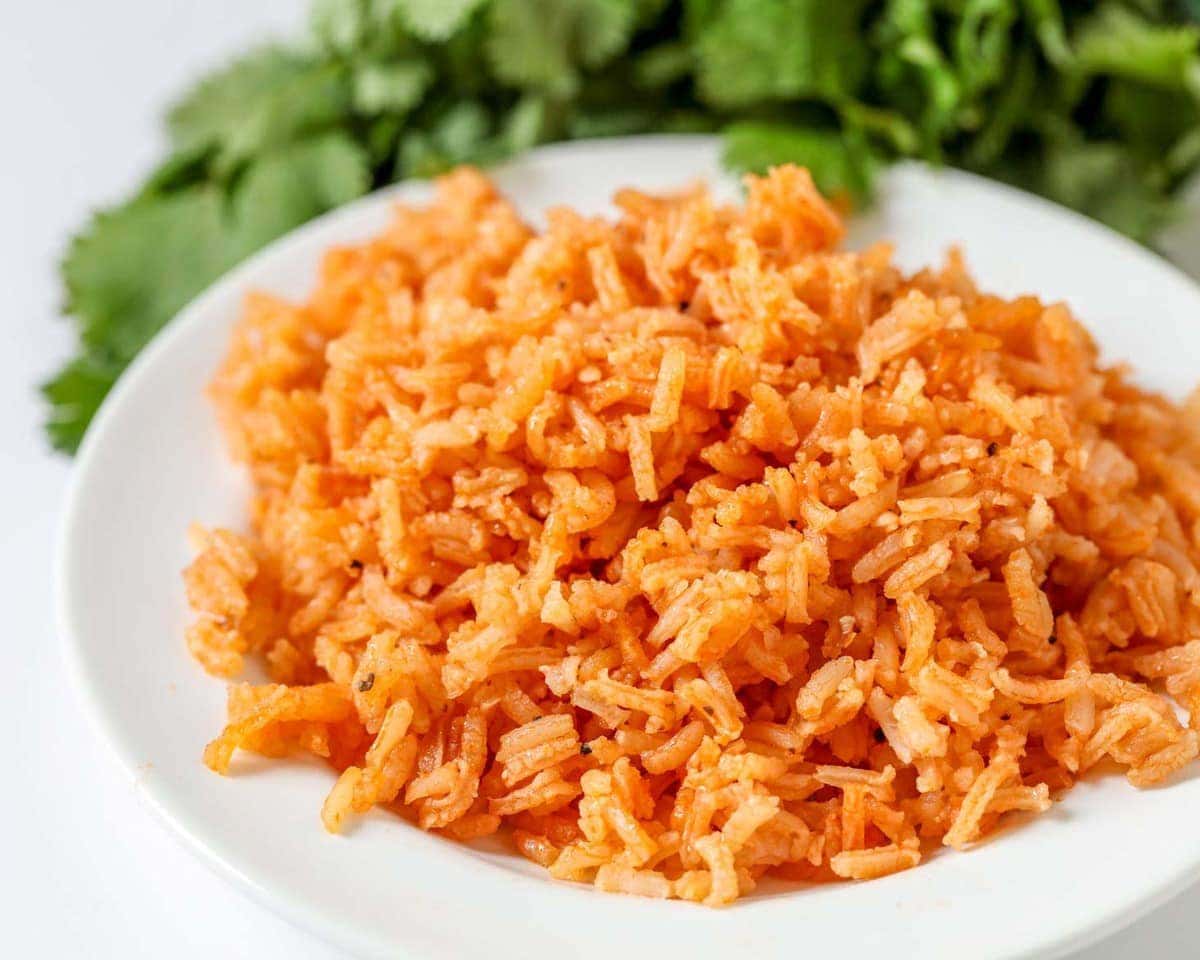 Homemade Spanish rice on a plate with fresh cilantro in the background.