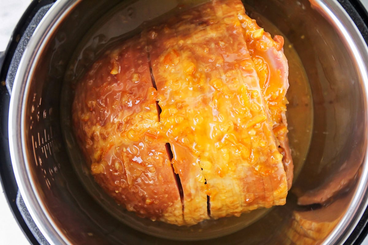 Cooked ham with a glaze inside the instant pot to be cooked.