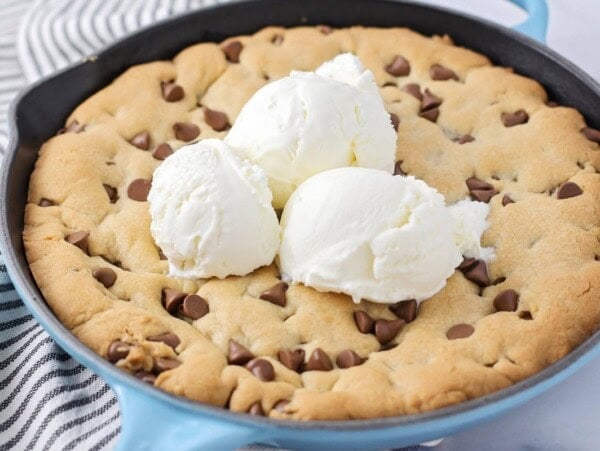 Easy Pizookie recipe cooked up in cast iron skillet with ice cream on top.