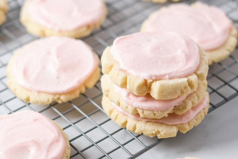 Frosted copycat swig sugar cookies stacked on a cooling rack.