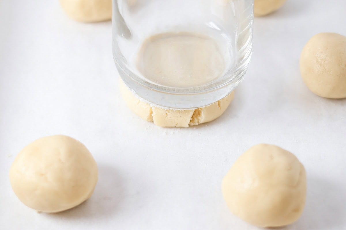 Glass cup pressing dough balls into rounds.