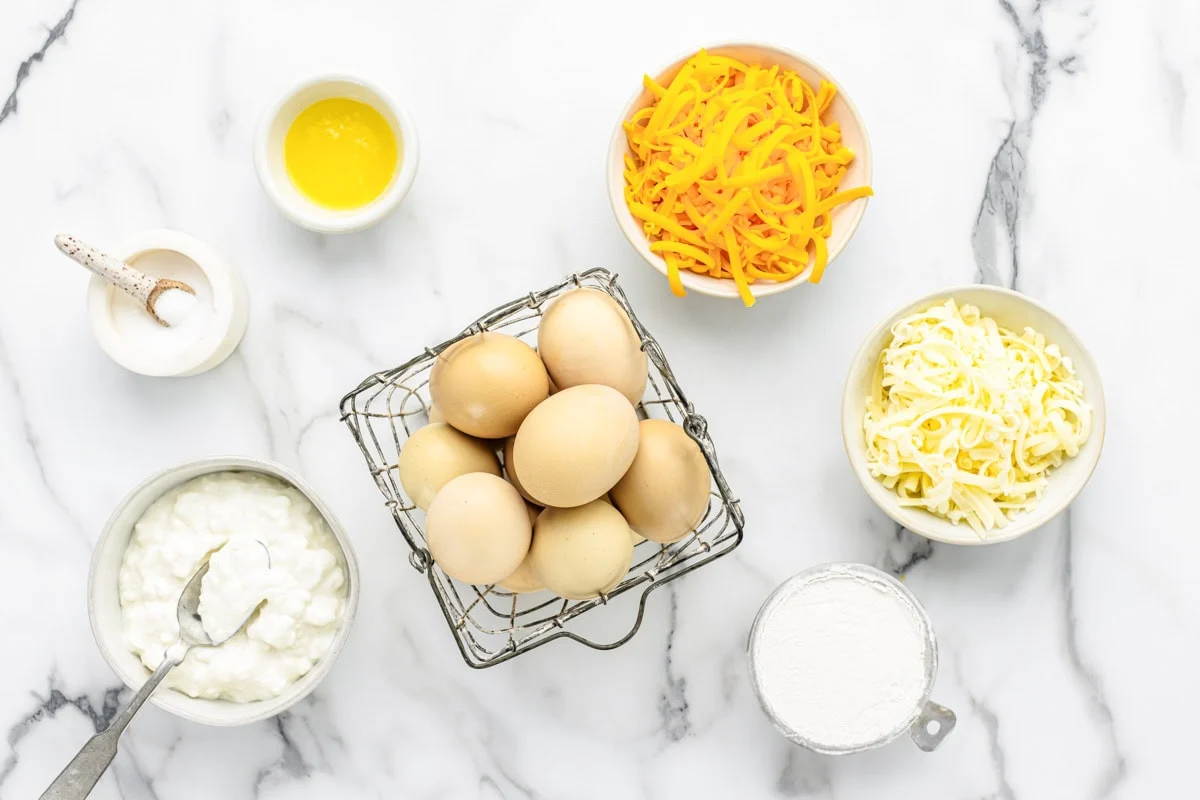 Eggs, cheese, and seasoning measured on a kitchen counter.