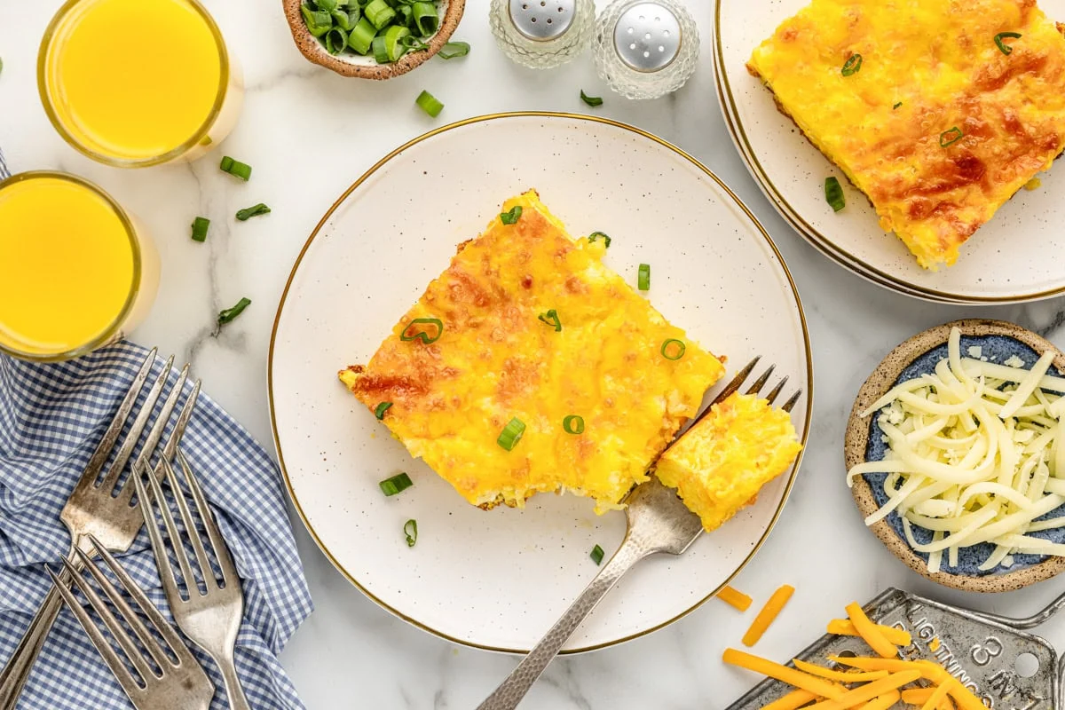 A slice of baked eggs on a white plate topped with green onions.