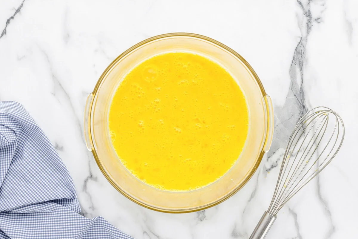 Eggs whisked in a glass bowl.