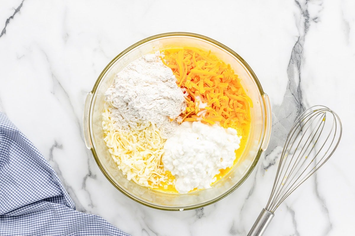 Adding cheese and flour to the egg mixture.