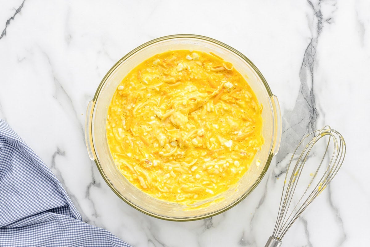 Whisked eggs and cheese in a glass bowl.