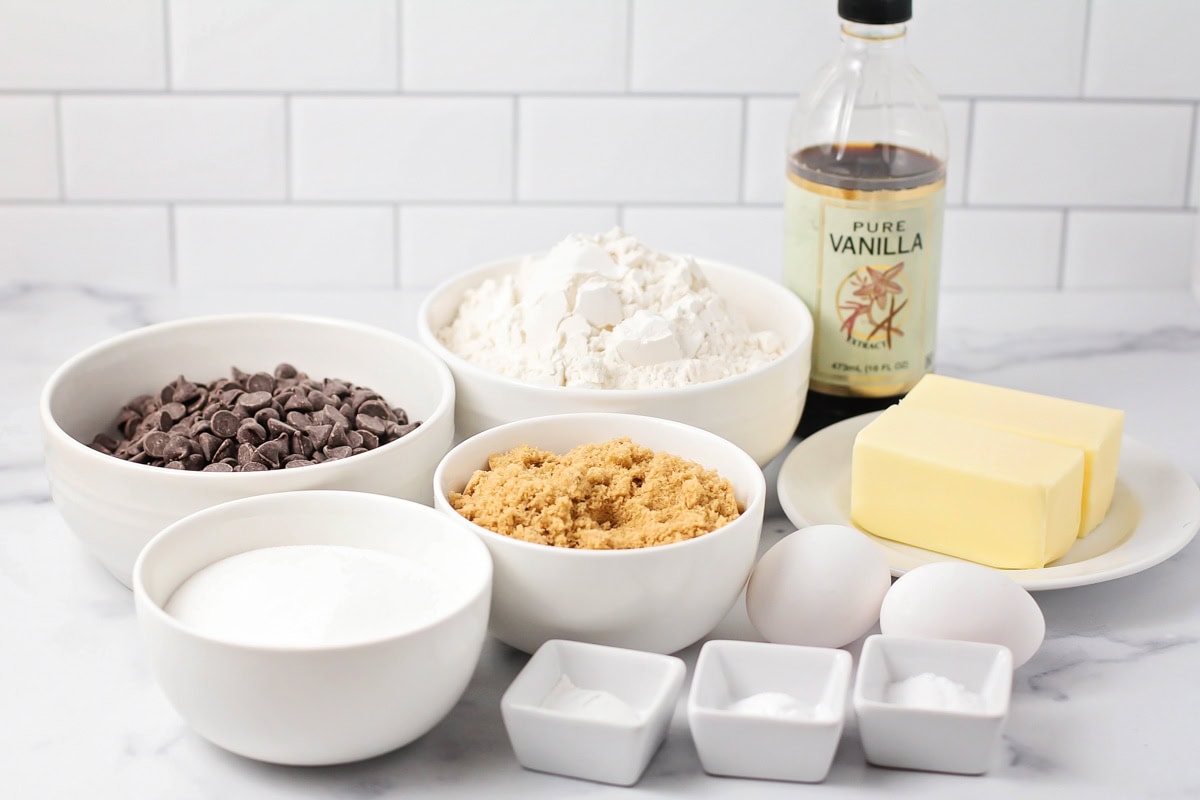 Flour, sugar, eggs, vanilla, chocolate chips on a kitchen counter. Ingredients for chocolate chip cookies.