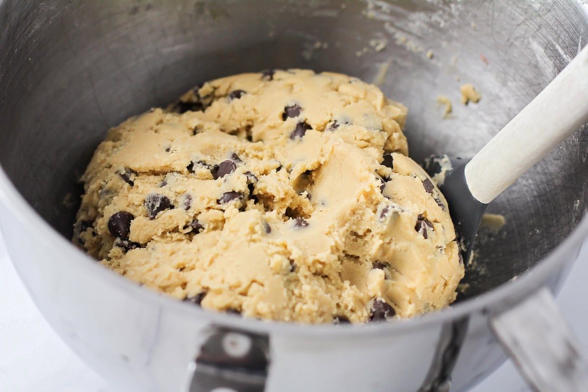 Chocolate chip cookie dough in a metal bowl.