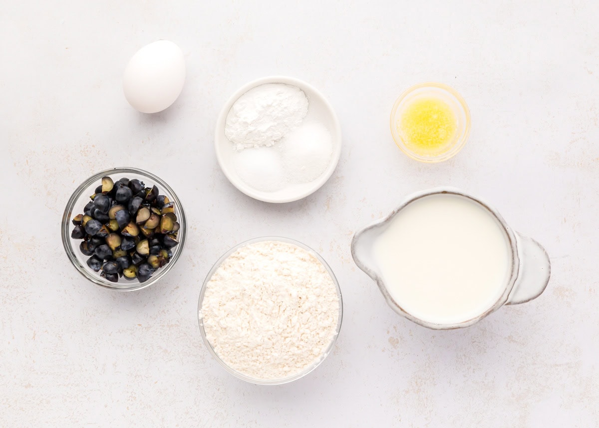 Flour, sugar, egg, blueberries, and other ingredients on a kitchen counter.