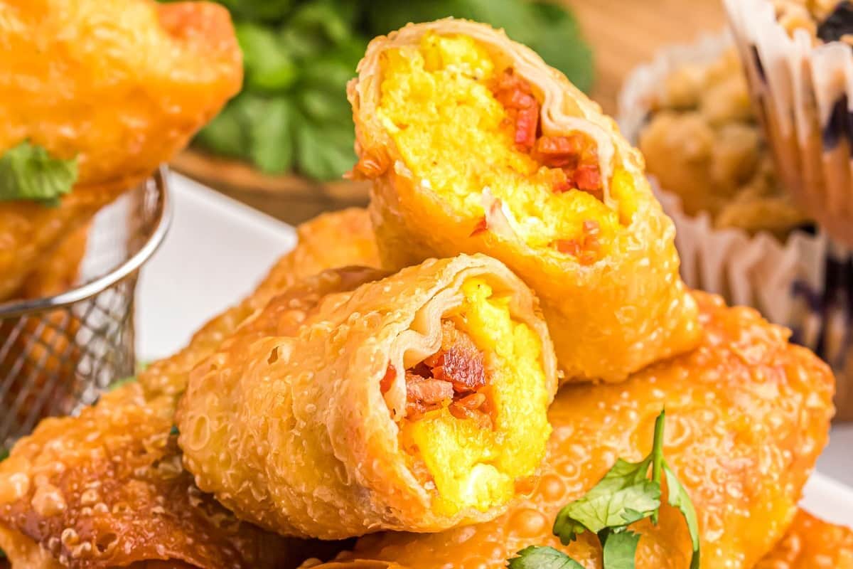 A crispy breakfast egg roll cut in half and stacked on other egg rolls.