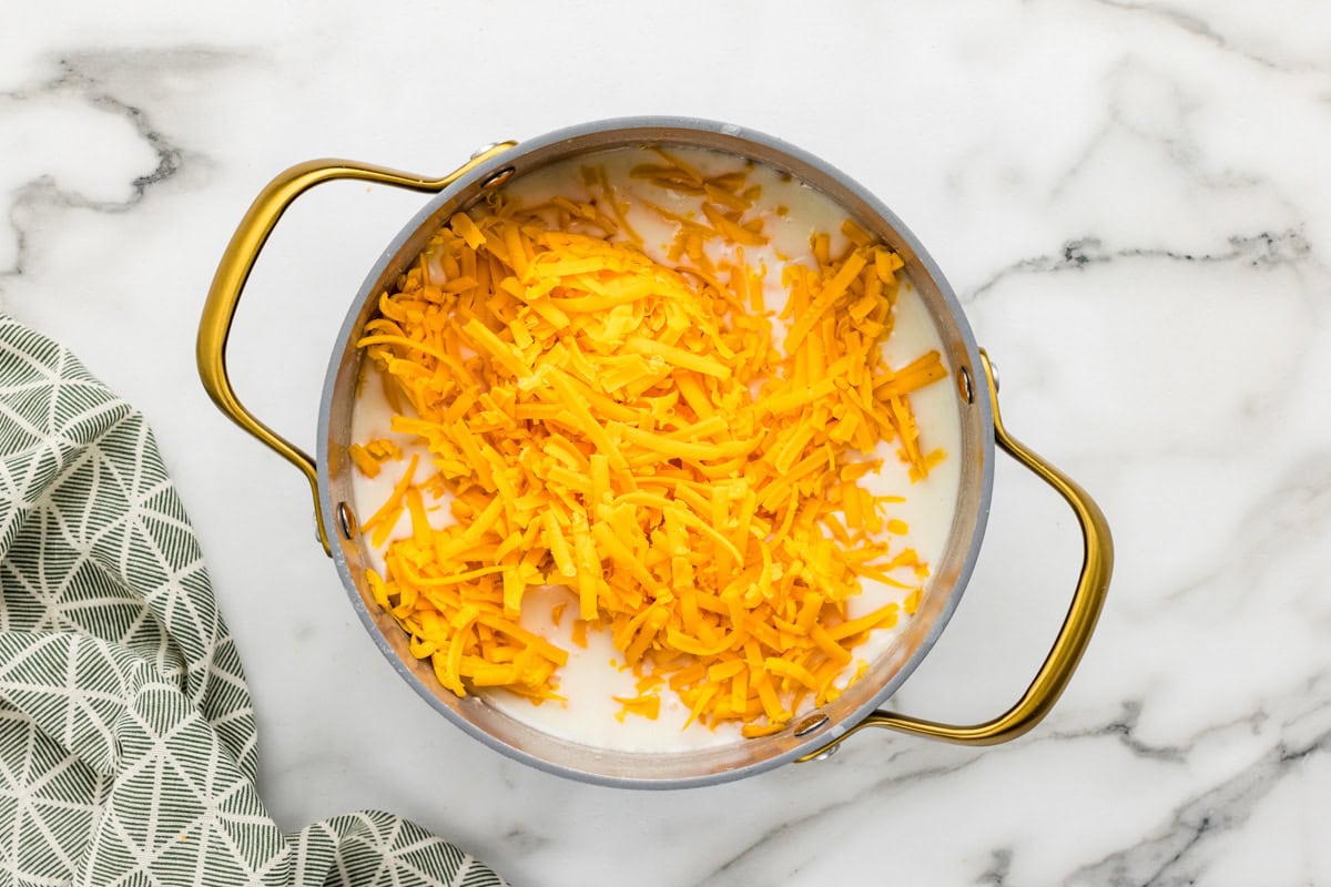 Cheese poured into pot for broccoli cheese potato soup recipe.