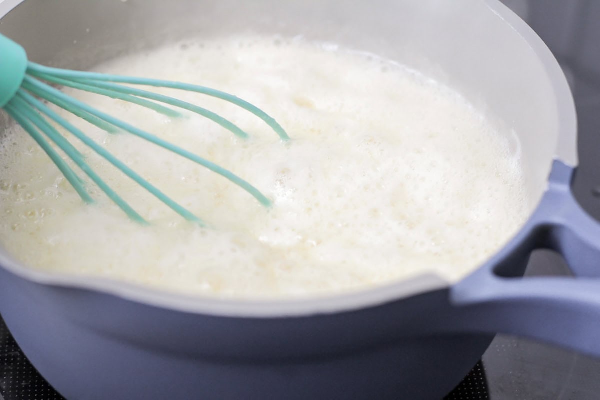 Foamy mixture of buttermilk syrup cooking in pot.