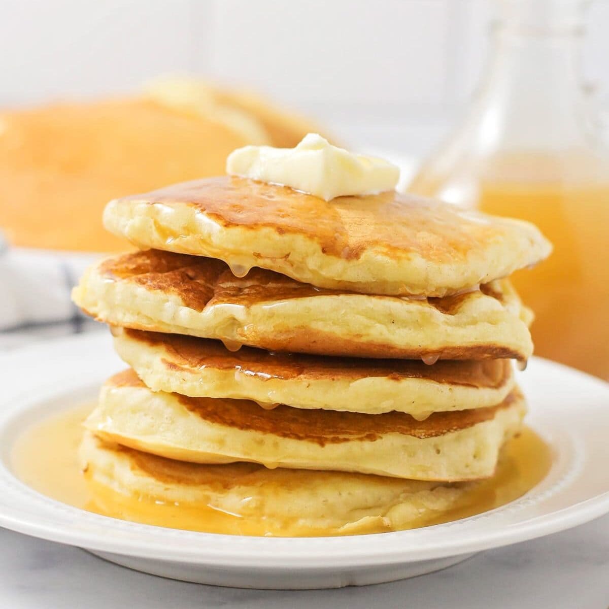 Stacked pancakes with buttermilk syrup poured all over it.