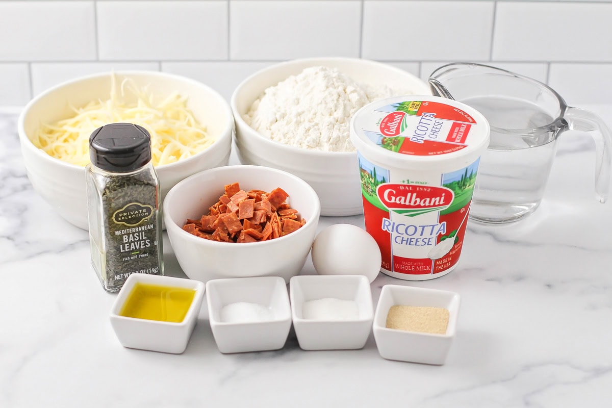 Ricotta, pepperoni, cheese, and other ingredients on a kitchen counter.