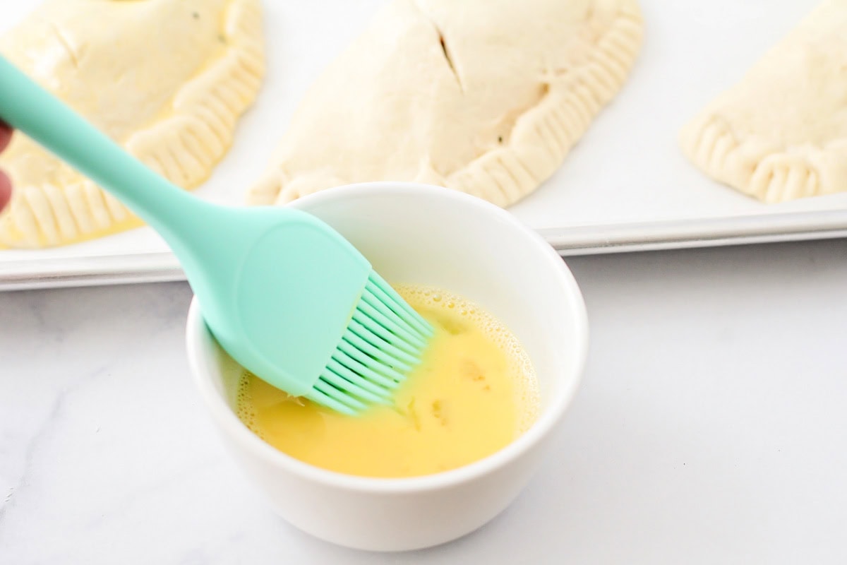 Brushing calzones with an egg wash.