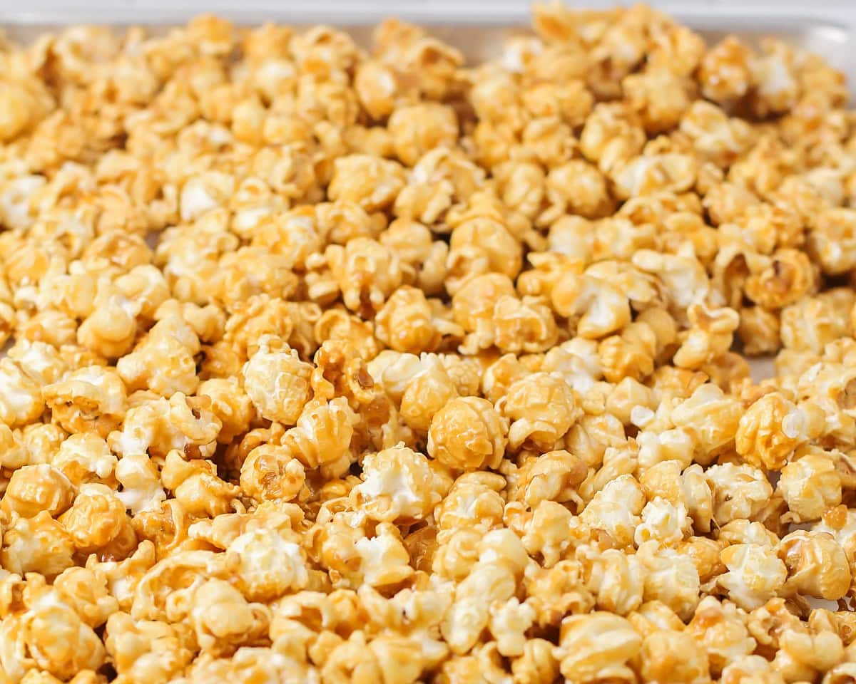 Homemade caramel popcorn spread out on a baking sheet.