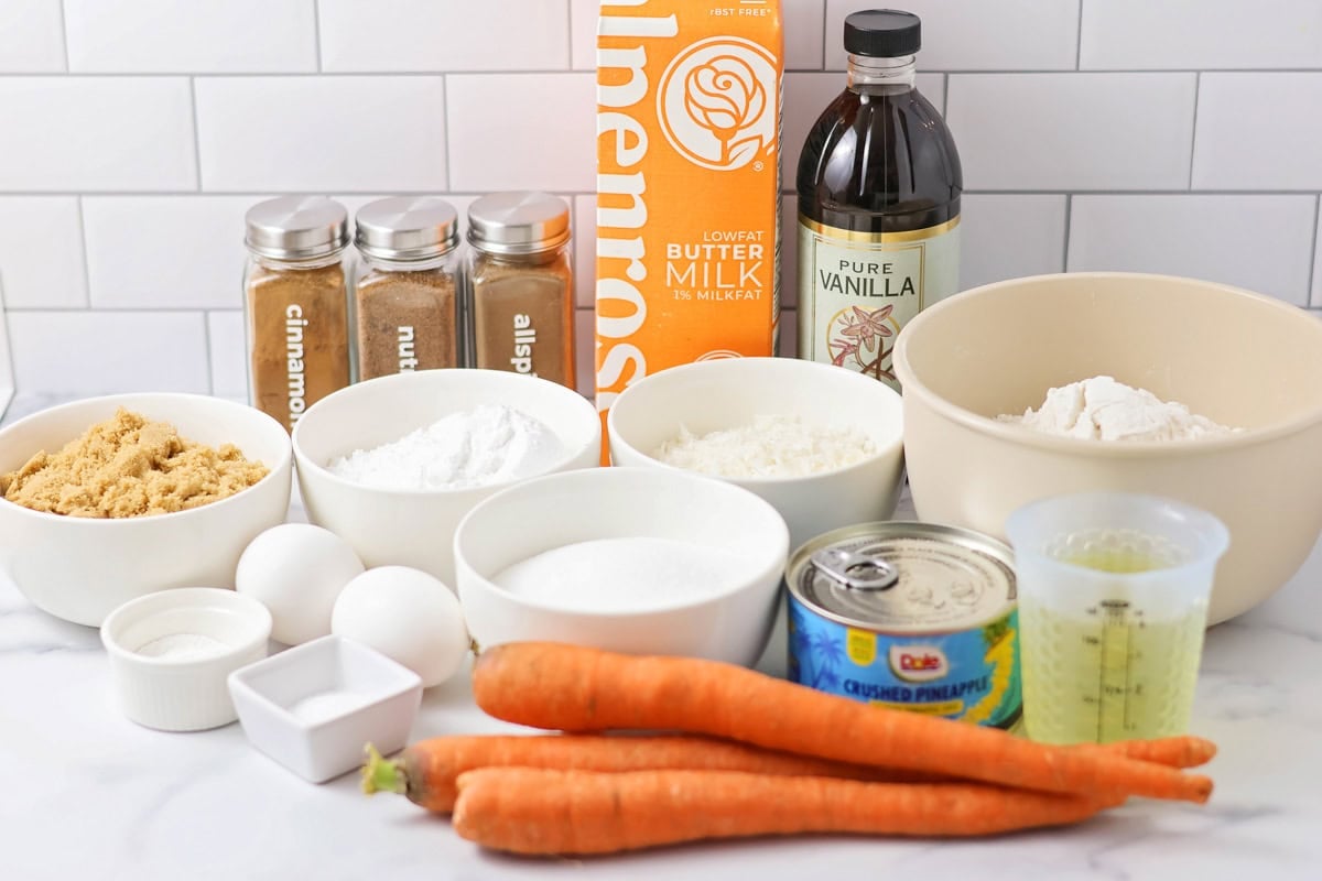 Ingredients for carrot cake muffins on a white countertop.