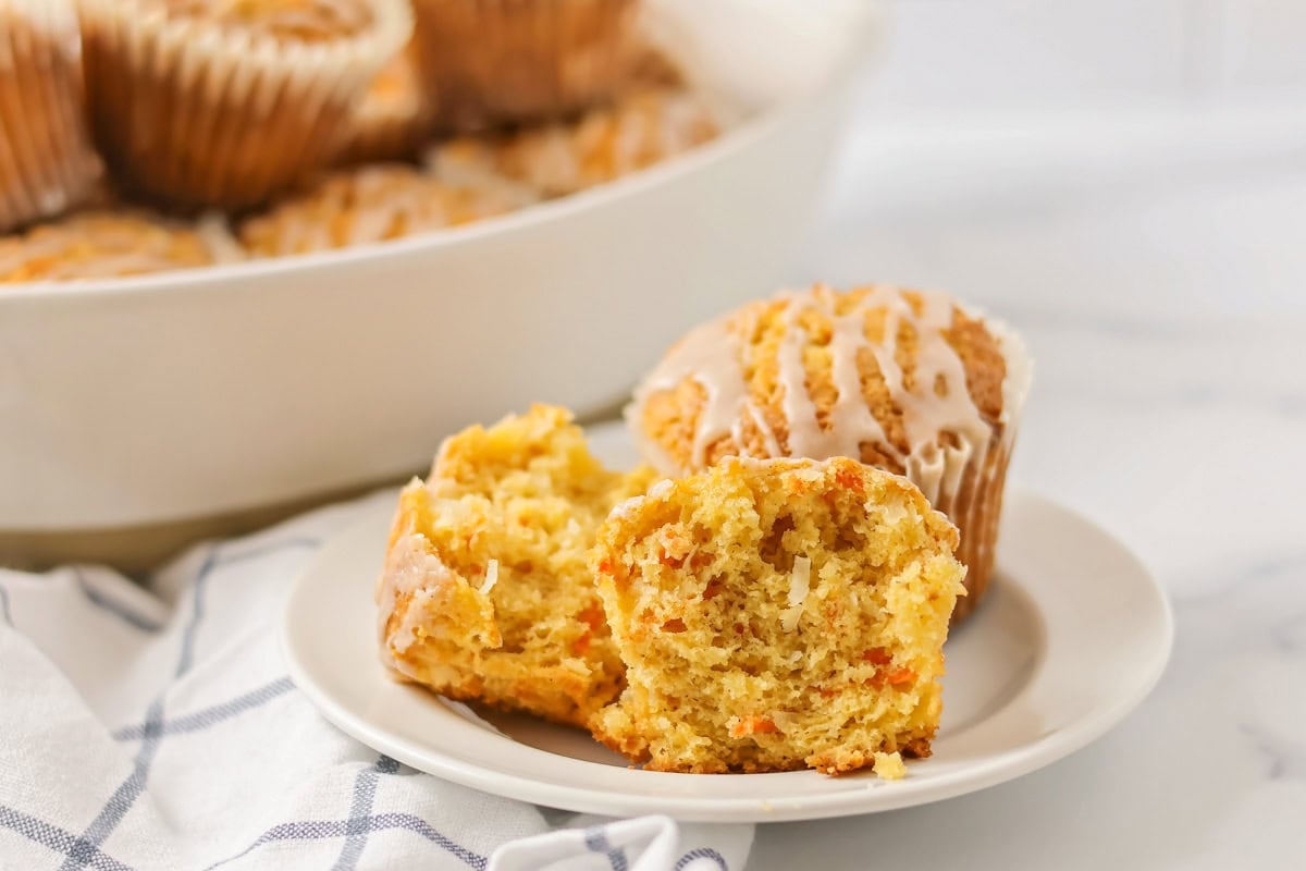 A muffin broken in half on a white plate.